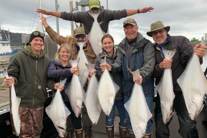 a group of people standing next to a person holding a fish